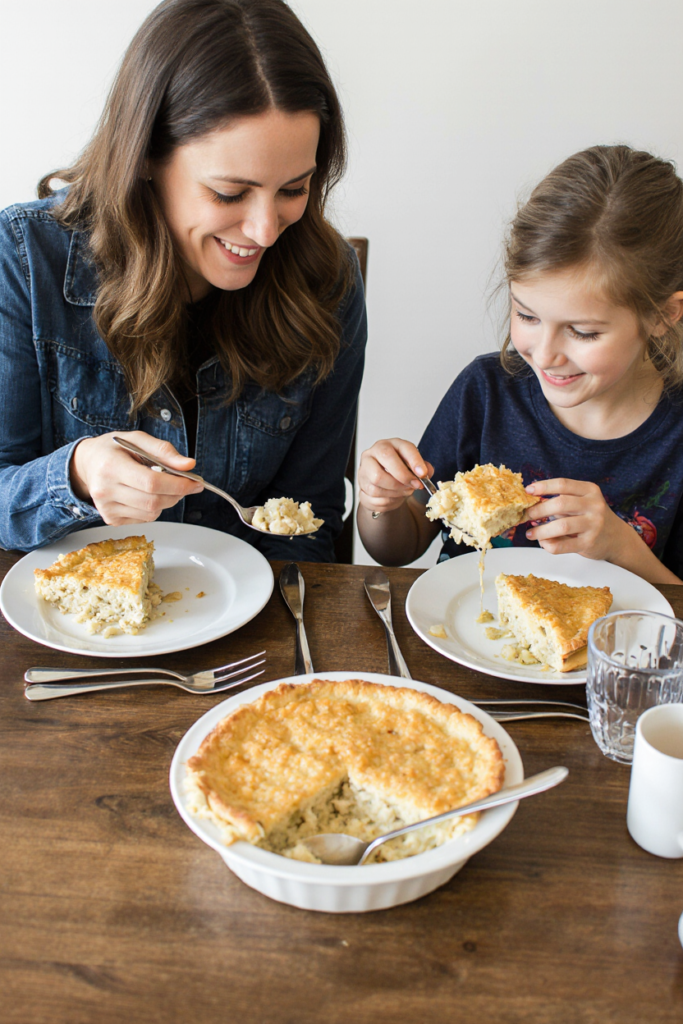 Mother and child enjoying homemade chicken pot pie at the dinner table.